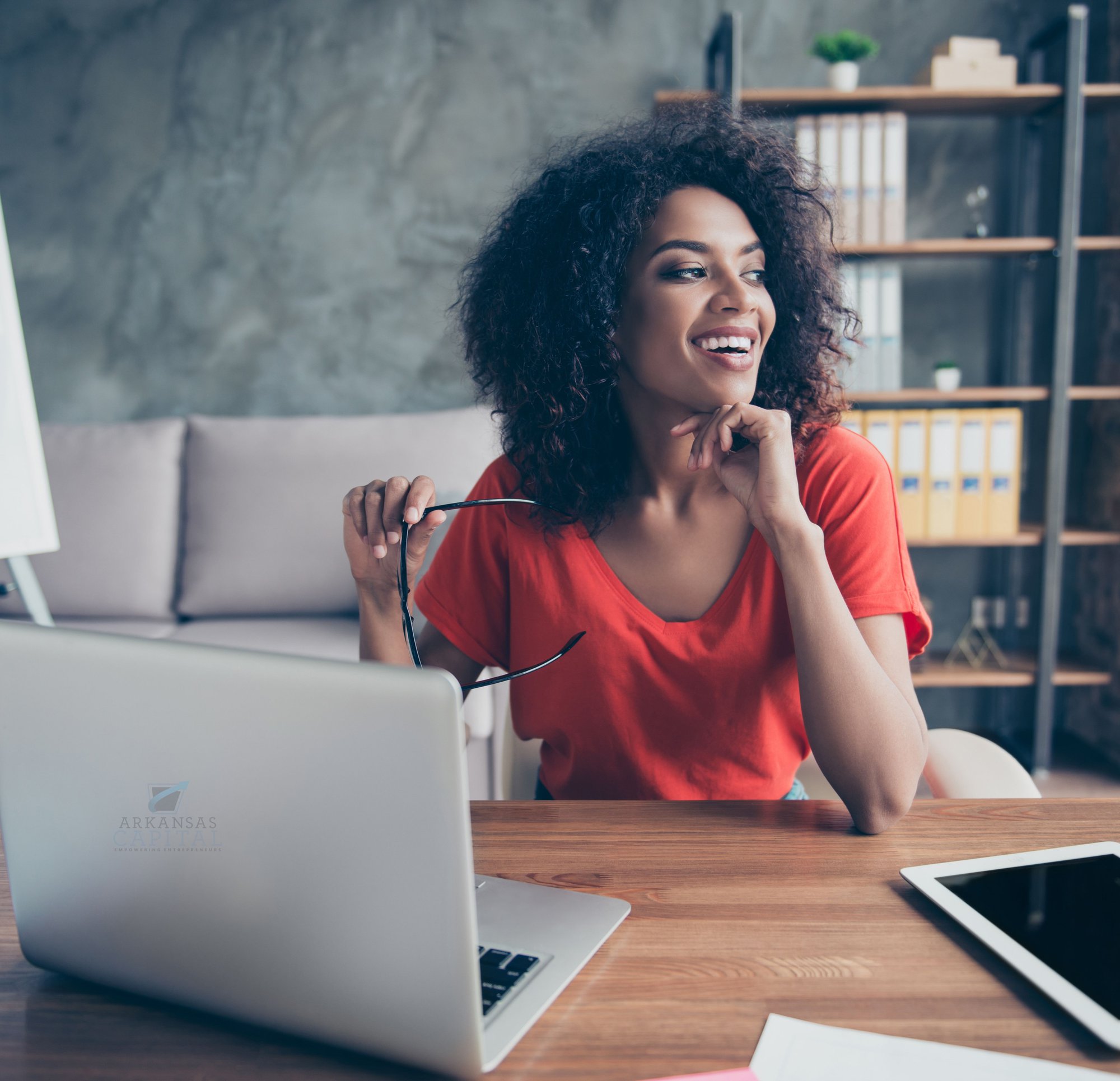 A happy woman look away from her laptop as she begins the process of discovering what New Market Tax Credits are.